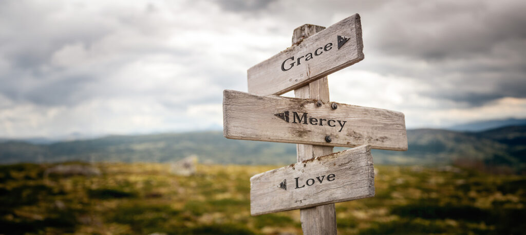 grace mercy love text engraved on old wooden signpost outdoors in nature. Quotes, words and illustration concept